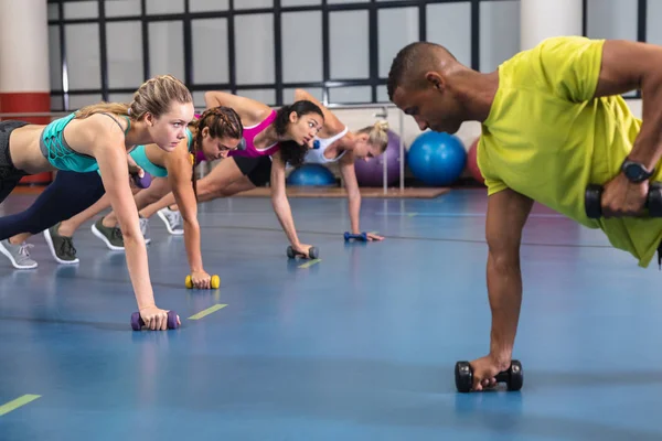 非洲裔美国男性培训师训练女性在健身中心练习哑铃的侧视图 健康的人锻炼身体和训练的明亮的现代体育馆 — 图库照片