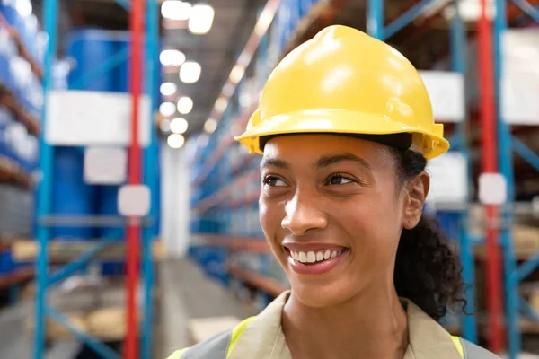 倉庫で笑顔のハードハットを持つ女性スタッフのクローズアップ — ストック写真