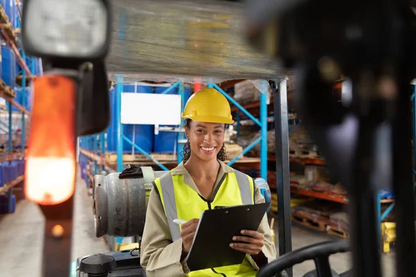 Portret Van Vrouwelijk Personeel Schrijven Klembord Terwijl Zittend Vorkheftruck Magazijn — Stockfoto