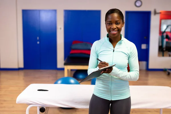 Gelukkige Vrouwelijke Trainer Die Naar Camera Kijkt Tijdens Het Schrijven — Stockfoto