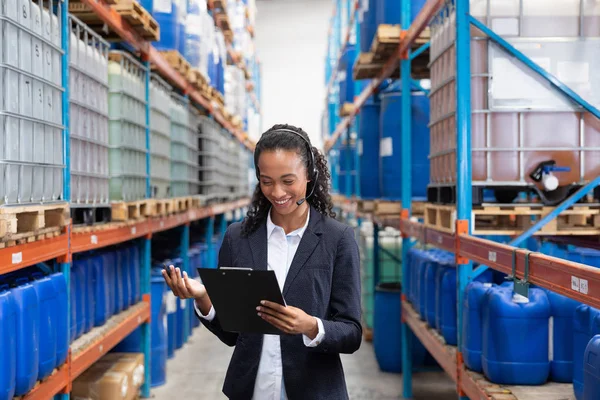 Gelukkige Vrouwelijke Manager Met Headset Schrijven Klembord Magazijn — Stockfoto