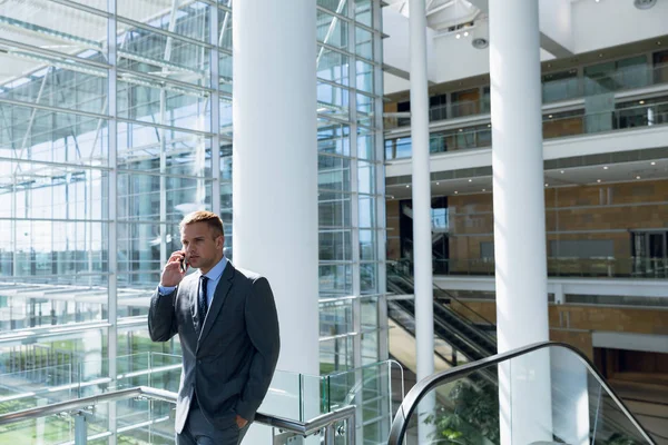 オフィスの廊下で携帯電話で話してるビジネスマン — ストック写真