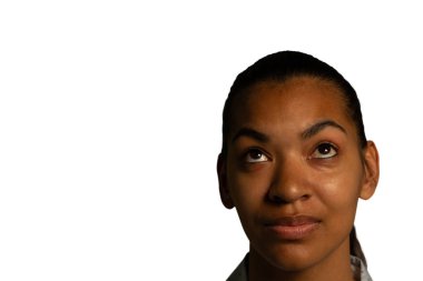 Head shot of a young mixed race woman with eyes looking up to her right clipart