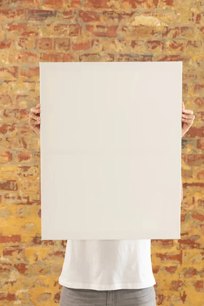 前视图中 人们手握空白的白色帆布 面对着镜头 站在砖墙前 — 图库照片