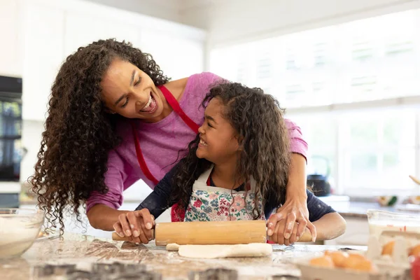 クリスマスに彼女の若い娘と台所で混合人種の女性の正面図 クッキーを作る 生地を転がし お互いを見て — ストック写真
