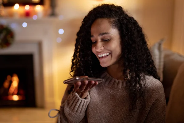 圣诞节时 一个混血女人在客厅里 在智能手机上交谈 面带微笑 — 图库照片