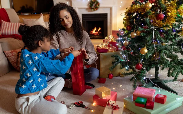 クリスマスの間 彼女の若い娘と一緒に床に座っている混合人種の女性の正面図 笑顔とラッピングプレゼント — ストック写真