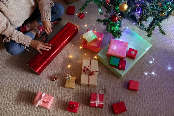 圣诞节时 坐在地板上 包装礼物 在客厅里 妇女的前视图中段 — 图库照片