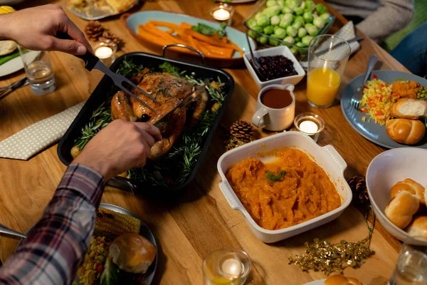 高角度看男人的手坐在一张桌子上感恩节晚餐在家里雕刻火鸡 — 图库照片
