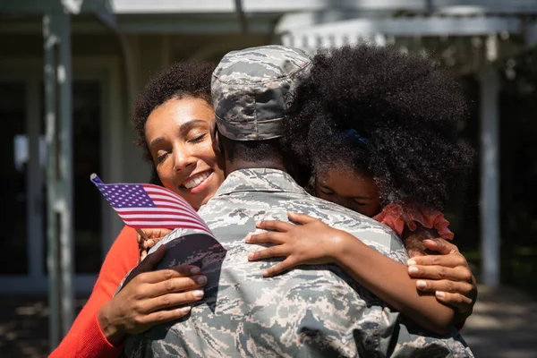 一个年轻的非裔美国士兵紧紧地拥抱着他的小女儿和他的混血儿妻子 — 图库照片