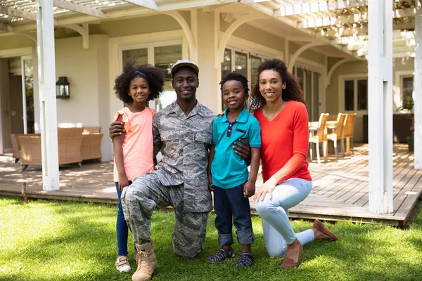 一个年轻的非洲裔美国士兵在自家花园外的画像 他抱着他年幼的儿子和女儿跪在地上 身旁的是他的混血儿妻子 他们都在镜头前微笑着 — 图库照片