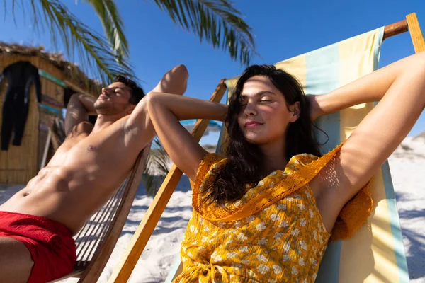 晴れた日にビーチで時間を楽しむ白人のカップル 背景に青い空とデッキチェアや日光浴に座って — ストック写真
