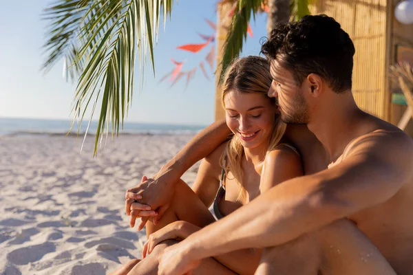 晴れた日にビーチで時間を楽しむ白人夫婦 ヤシの木に座って 背景に海と抱擁 — ストック写真