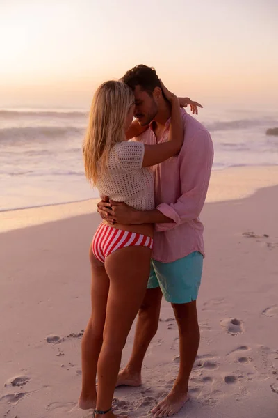 白种人夫妇在美丽的夕阳西下的海滩上享受时光 在蓝天和大海的映衬下拥抱和亲吻 — 图库照片