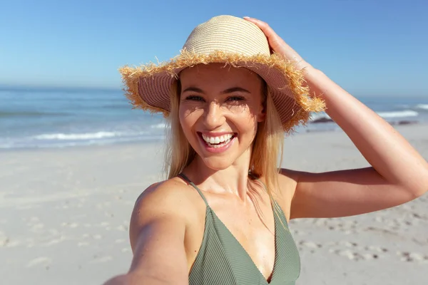 一个白种人女人在阳光灿烂的日子里享受海滩时光的画像 她看着相机 面带微笑 背对着大海 — 图库照片