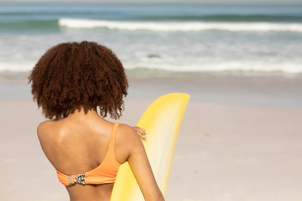 在阳光明媚的日子里 一名混血女子穿着泳衣 在沙滩上散步 背着冲浪板 在海滩上享受闲暇时光的背影 — 图库照片