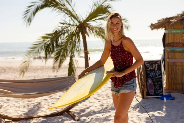 白人女性は晴れた日にビーチで時間を楽しみ サーフボードを持ち カメラを見て微笑んだ — ストック写真
