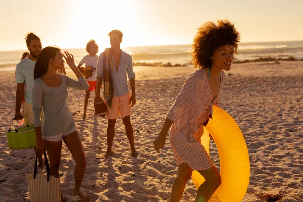 在阳光灿烂的日子里 一群多种族的朋友在海滩上共度时光 赤脚散步 彼此交谈 — 图库照片
