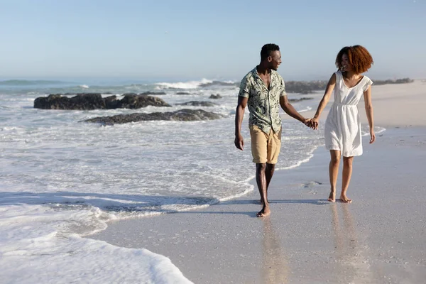 在阳光灿烂的日子里 一对混血的夫妇在海滩上共度时光 手牵手散步 — 图库照片