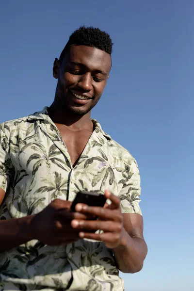 在阳光明媚的日子里 非裔美国人在海滩上享受着闲暇时光 他们站在那里 用智能手机 微笑着 — 图库照片