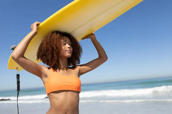 在阳光灿烂的日子里 一位迷人的混血女子穿着泳衣 在沙滩上散步 背着冲浪板 在海滩上享受着闲暇时光 — 图库照片