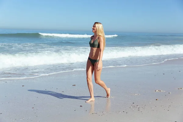 迷人的金发白人女人在阳光明媚的日子里 在沙滩上散步 背景是蓝天蓝海 享受着沙滩上的时光 夏季热带海滩假期 — 图库照片