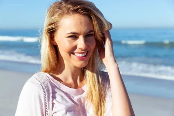 在阳光灿烂的日子里 迷人的金发白人女性在海滩上享受时光的画像 看着相机 微笑着 背景是蓝蓝的天空和大海 夏季热带海滩假期 — 图库照片