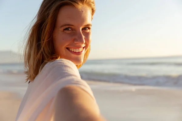 迷人的金发白人女人在日落时享受海滩上的时光 看着相机 微笑着 背景是夕阳西下的天空和大海 夏季热带海滩假期 — 图库照片