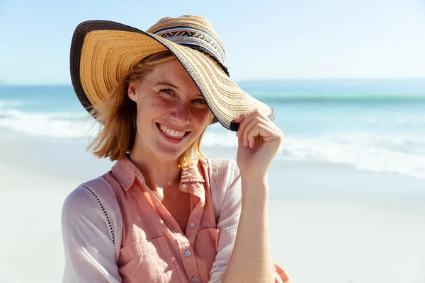 魅力的なブロンドの白人女性の肖像画晴れた日にビーチで時間を楽しんで 帽子をかぶって カメラを見て 青い空と海を背景にしています 夏の熱帯のビーチ休暇 — ストック写真