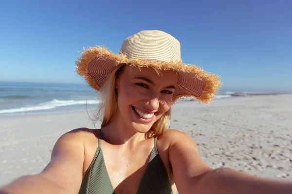 魅力的なブロンドの白人女性の肖像画晴れた日にビーチで時間を楽しんで 太陽の帽子をかぶって カメラを見て 青い空と海を背景にしています 夏の熱帯のビーチ休暇 — ストック写真