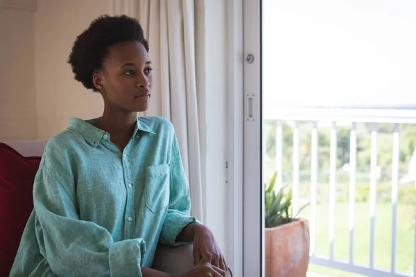 混合人種の女性は自宅で時間を過ごし 彼女の寝室に座って窓の外を見ています コロナウイルスの間の隔離されたロックダウンでの自己隔離と社会的距離は19の流行をCovid — ストック写真