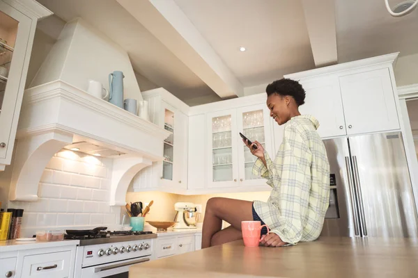 여성은 집에서 시간을 보내고 부엌에 스마트폰을 합니다 코로나 바이러스가 유행하는 — 스톡 사진
