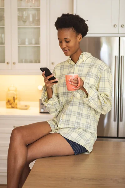 Smíšená Závodnice Tráví Čas Doma Sedí Své Kuchyni Používá Smartphone — Stock fotografie