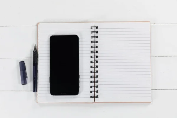 Close Vista Superior Smartphone Preto Notebook Uma Caneta Preta Dispostos — Fotografia de Stock