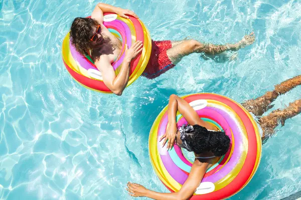 다양한 코카서스 남성과 아프리카계 미국인 여성은 다채로운 수영장에서 휴식을 있습니다 — 스톡 사진
