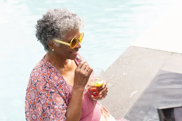 Senior Biracial Woman Enjoys Drink Pool Wearing Yellow Sunglasses Patterned — Stock Photo, Image