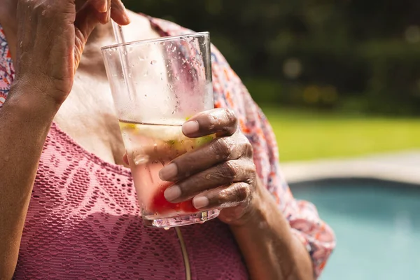 Senior Biracial Mujer Disfruta Una Refrescante Bebida Junto Piscina Mano Imágenes de stock libres de derechos