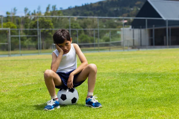 Biracial Pojke Sitter Fotboll Ser Ledsen Solig Plan Skolan Med Royaltyfria Stockfoton