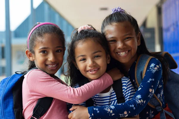 Tres Niñas Biraciales Sonríen Abrazan Entorno Escolar Los Niños Con Imagen de stock