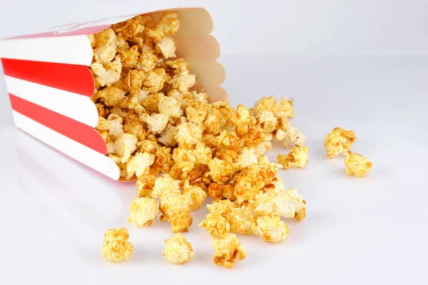 Popcorn in abgestreifter Röhrenverpackung auf hellem Hintergrund. — Stockfoto