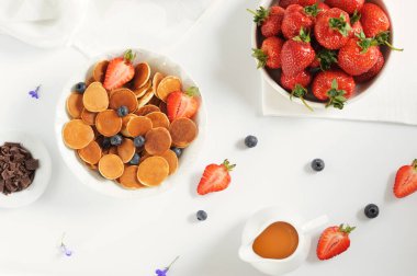 İçinde çikolata, bal, çilek ve böğürtlen olan küçük krepli ev yapımı tatlı bir kase. Düz yatıyordu. Yatay, seçici odak.