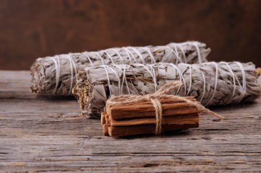 Kurumuş beyaz adaçayı lekesi ve palo santo eski ahşap arka plana yapışıyor. Enerji temizleme ve iyileştirme. Yazı için boşluk ile yatay yönelim. Seçici odak.