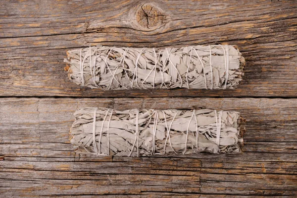 Dried white sage smudge bundles  on old distressed wood background.Aroma smoke for energy clearing and healing.Close up with space for text.