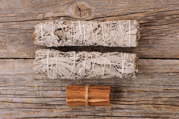 Dried white sage smudge bundles and palo santo sticks  on old  wooden background. Energy clearing and healing.Close up with space for text.
