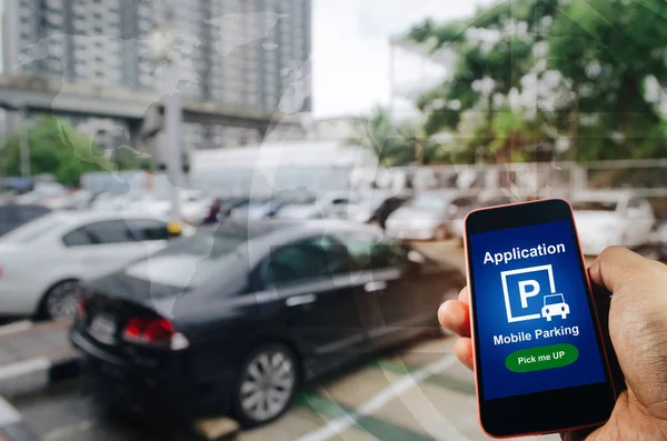 pick me up, mobile smart phone in hand using application for intelligent car park on blurred parking car outdoor background, mobile auto parking, online technology and internet connection concept