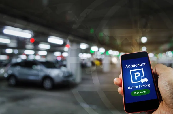 pick me up, mobile smart phone in hand using application for intelligent car park on blurred parking car indoor background, mobile auto parking, online technology and internet connection concept