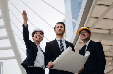 Grup iş ya da mühendis kadın ve yeni proje, başarılı konsepti başlangıç planlama adam kask ve binaya planlama ve modern şehir, çalışmalarını kontrol planı