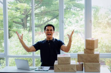 Başlamak yukarıya. genç adam yeni dizüstü bilgisayar, cep telefonu, teslim ambalaj kutusu tablo, evde çalışma office, KOBİ, küçük işletme sahibi ile müşteri online kavramı alışveriş siparişinden sonra mutlu