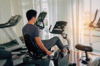 kas genç Asyalı adam onun bacakları kardiyo egzersizi bisiklet için iyi sabah, vücut geliştirme uzmanı, yaşam tarzı, sağlıklı fitness salonunda egzersiz egzersiz fitness, egzersiz ve spor eğitim kavramı