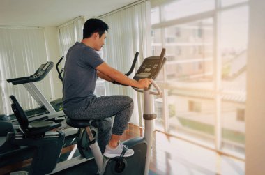 kas genç Asyalı adam onun bacakları kardiyo egzersizi bisiklet için iyi sabah, vücut geliştirme uzmanı, yaşam tarzı, sağlıklı fitness salonunda egzersiz egzersiz fitness, egzersiz ve spor eğitim kavramı